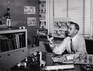 Photo of C. Carey Cloud circa 1944, at his desk playing with his many toys